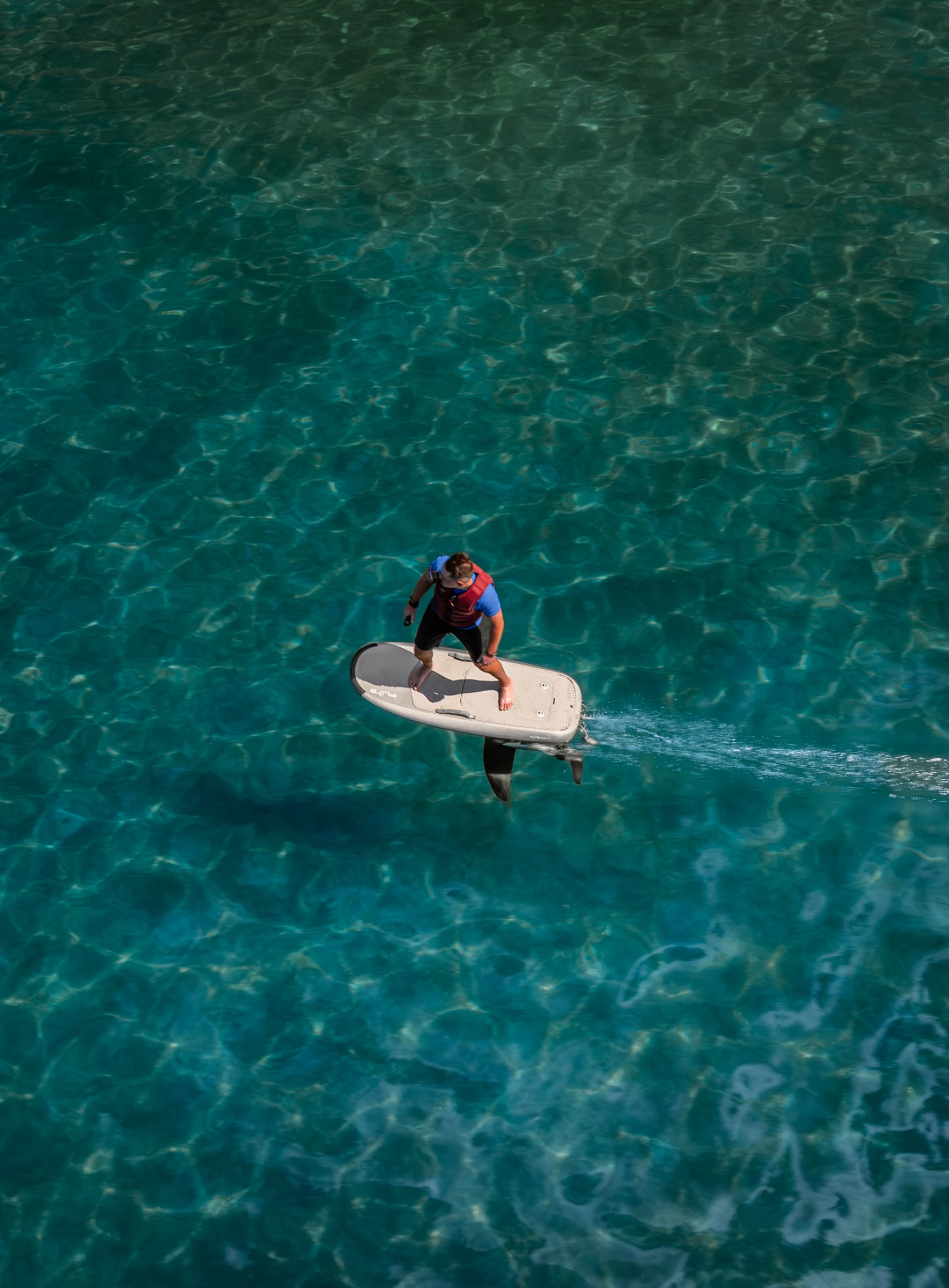 A guest gliding over clear turquoise water on an E-foil